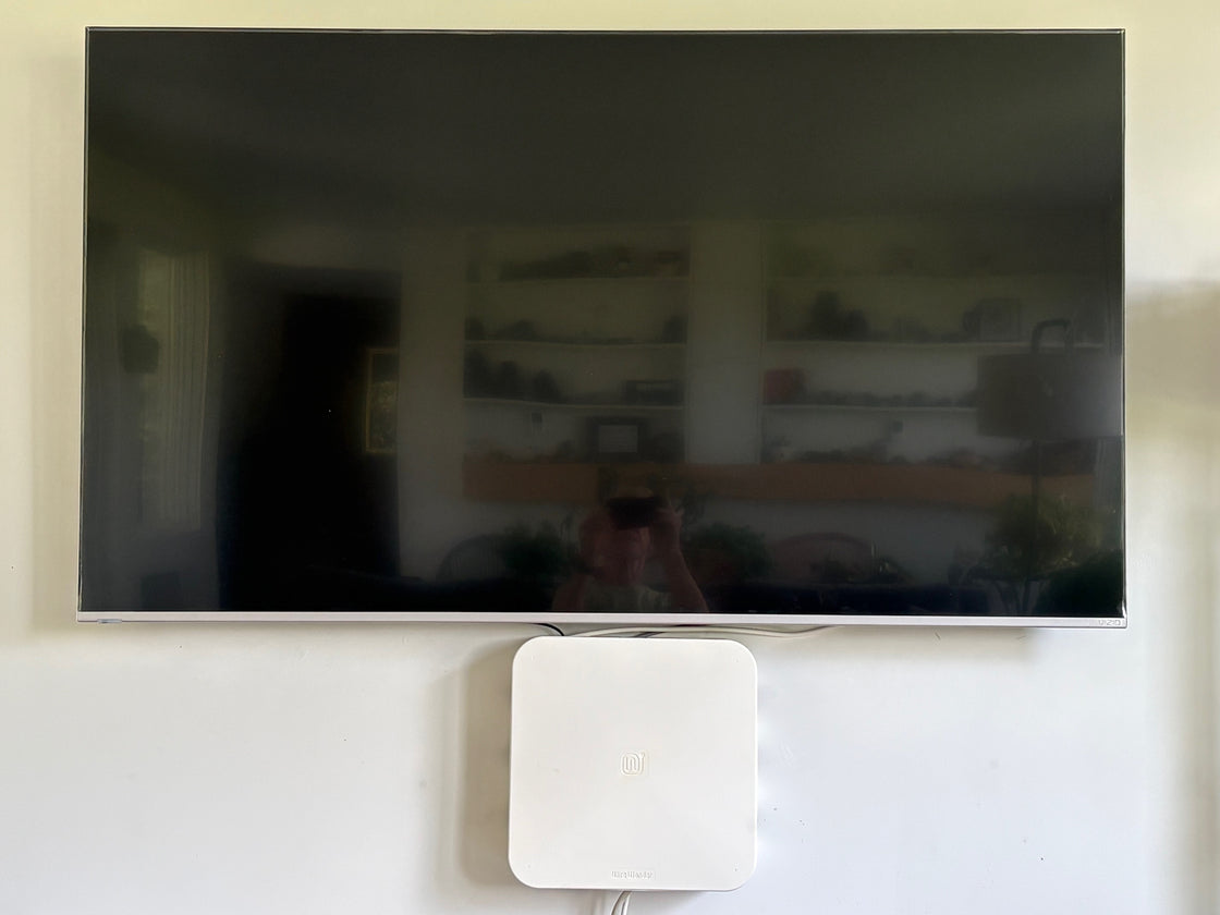 Wire Wonder mounted on the wall below a TV, concealing the TV power and AV cables
