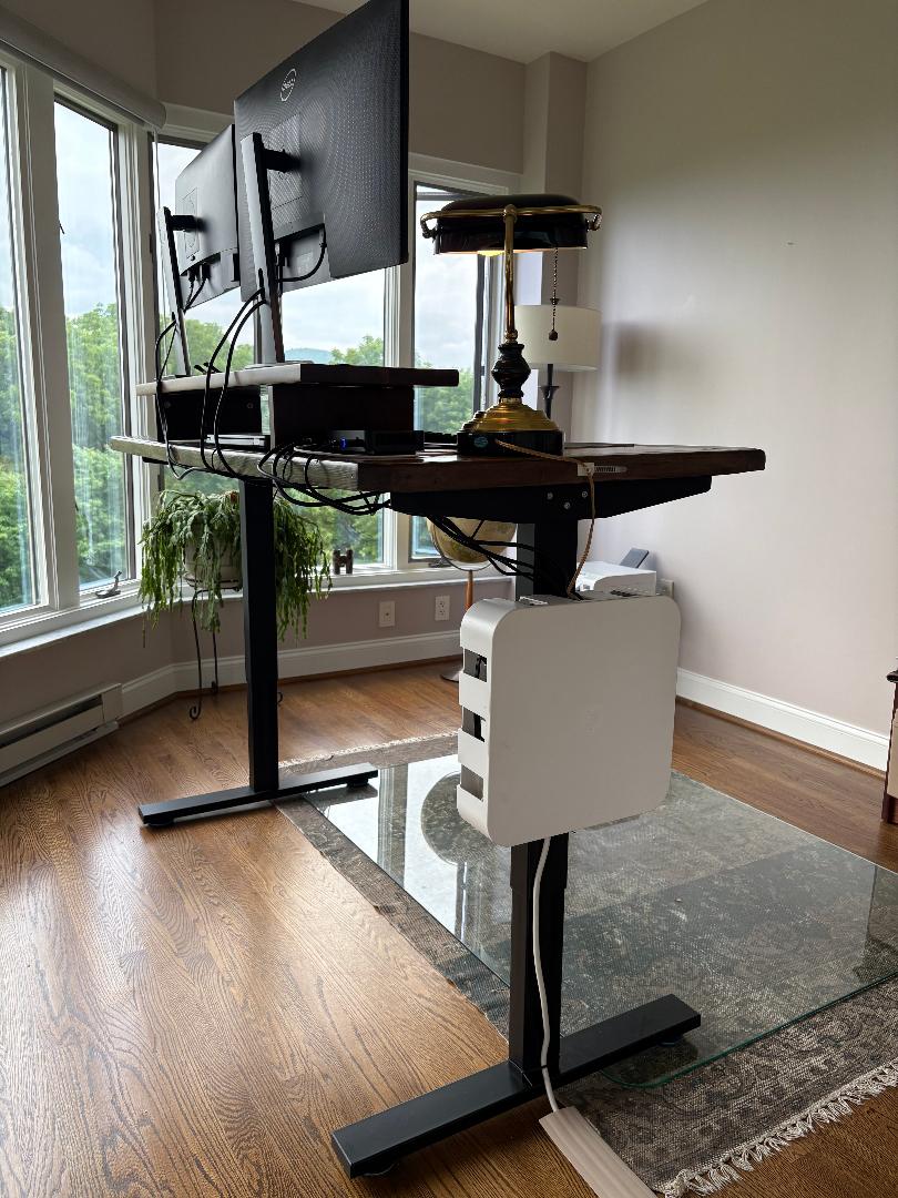 Wire Wonder cable management box mounted on the leg of a standing desk in a home office