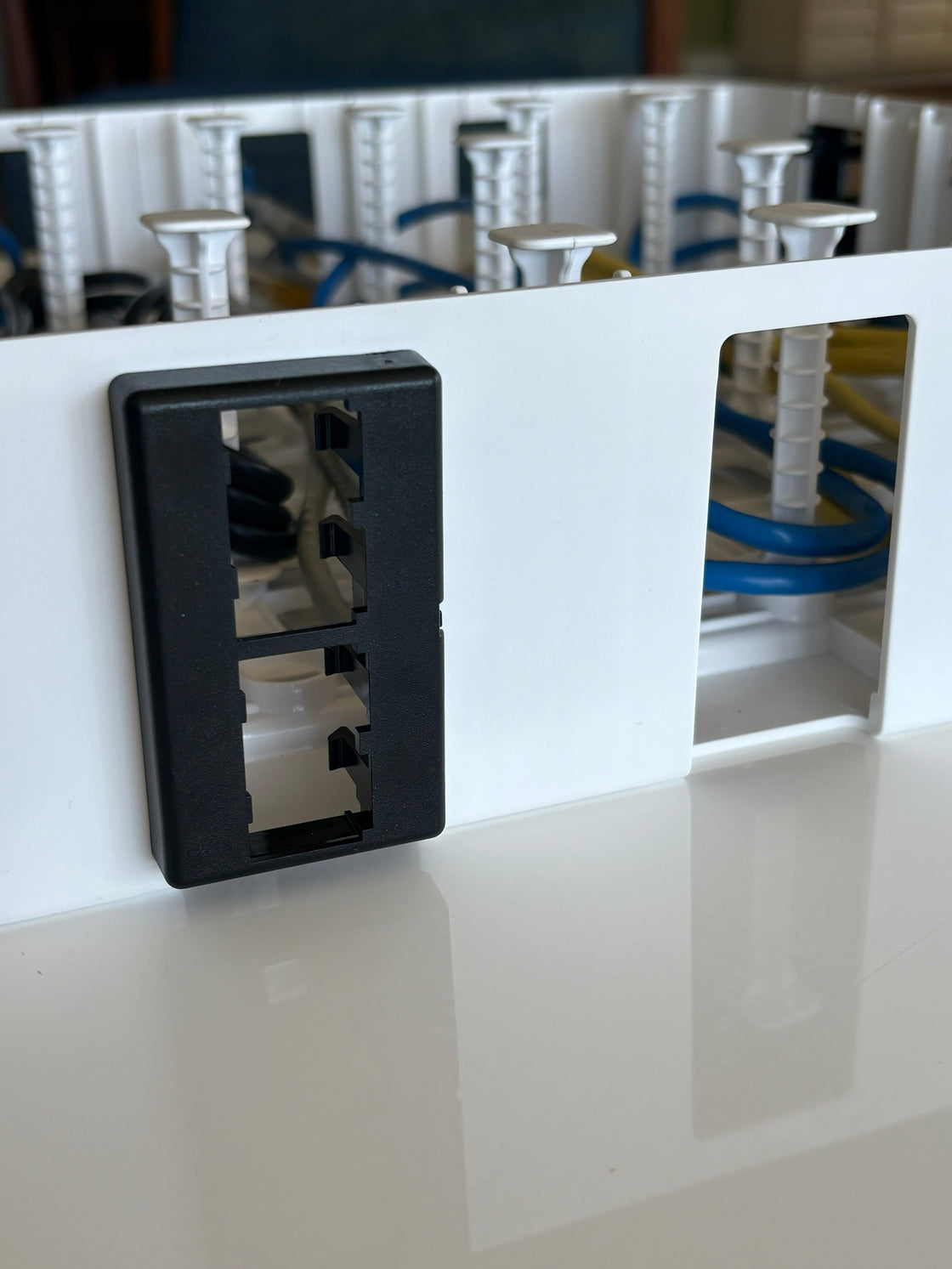 Furniture faceplate snapping into a sidewall slot of the Wire Wonder cable management box